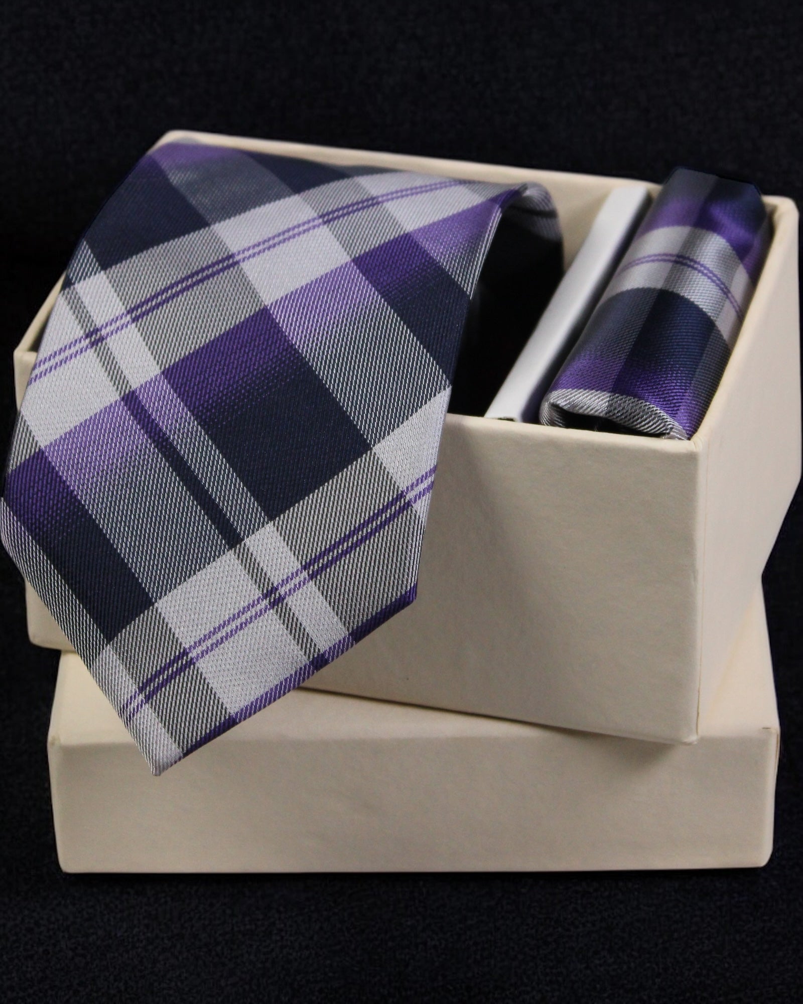 Plaid tie and pocket square set in a box on a black background