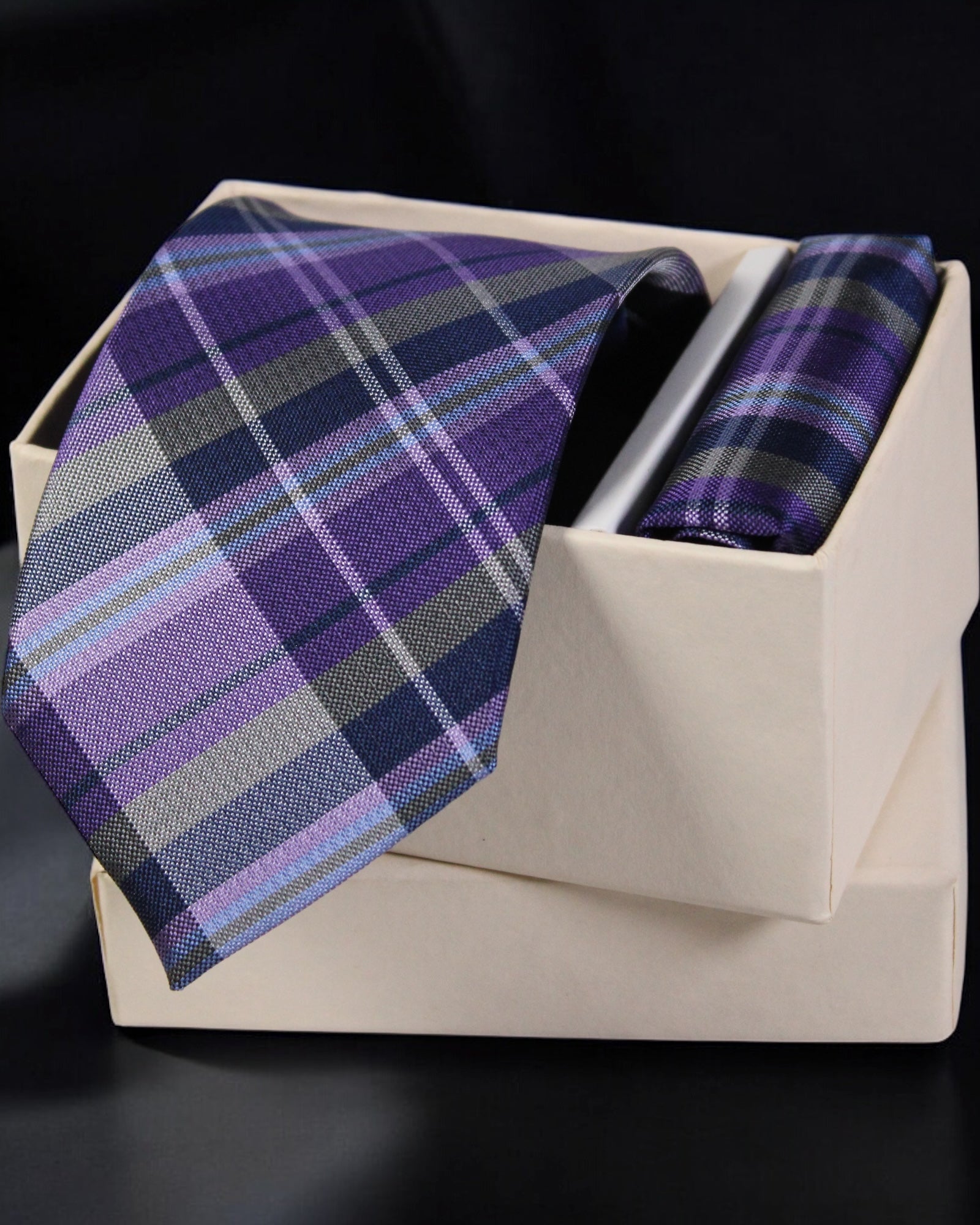 Purple plaid tie and pocket square set in a white box on a black background Tie Benon