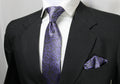 A mannequin wearing a black suit, displaying a gray and purple floral tie and a matching pocket square.