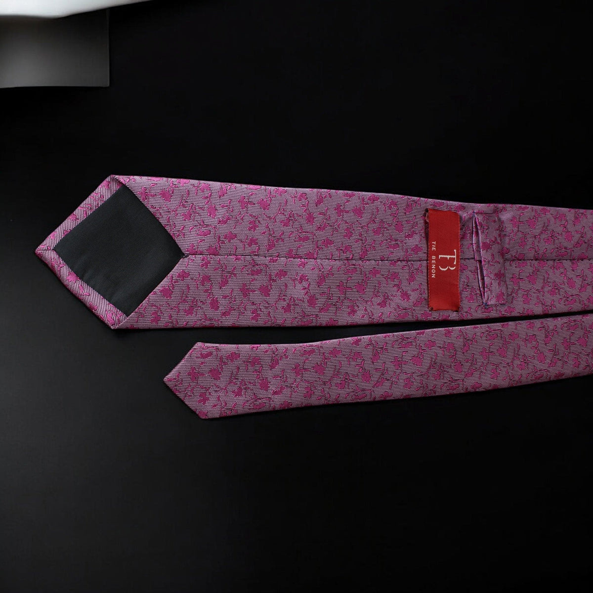Pink floral tie with a red label on a black background