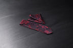 A black and maroon floral tie and pocket square set, laid out on a dark surface.