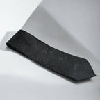 Black textured tie on a light gray background