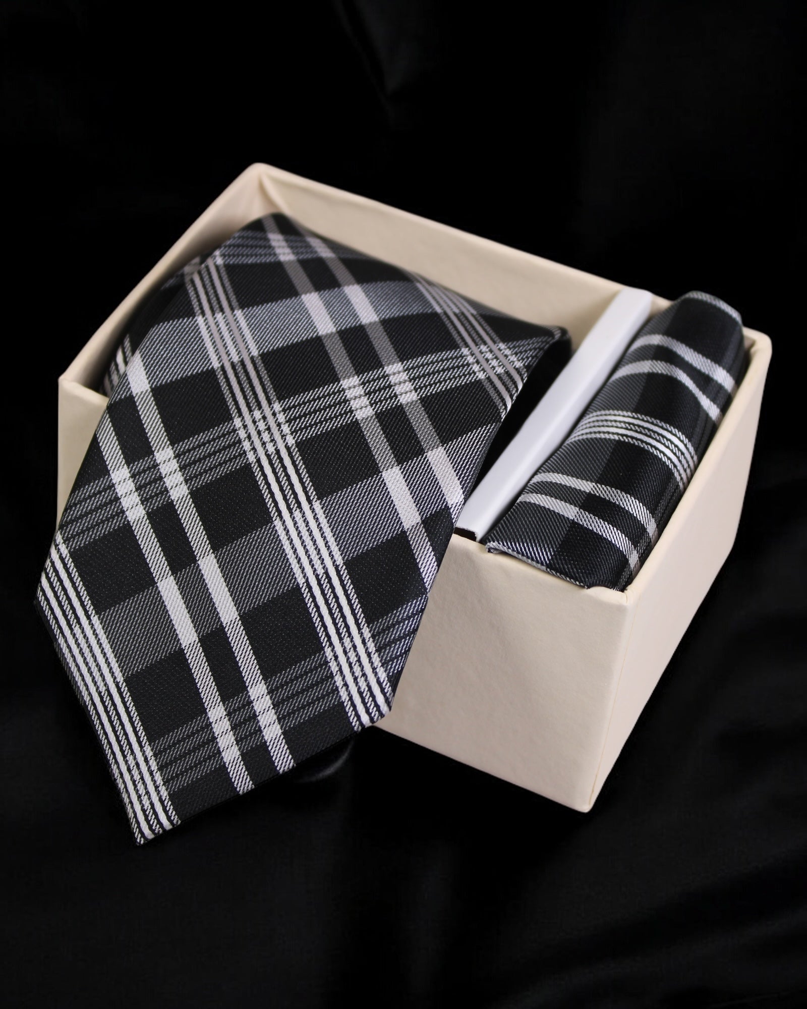 Black and white plaid tie and pocket square set in a beige box on a black background