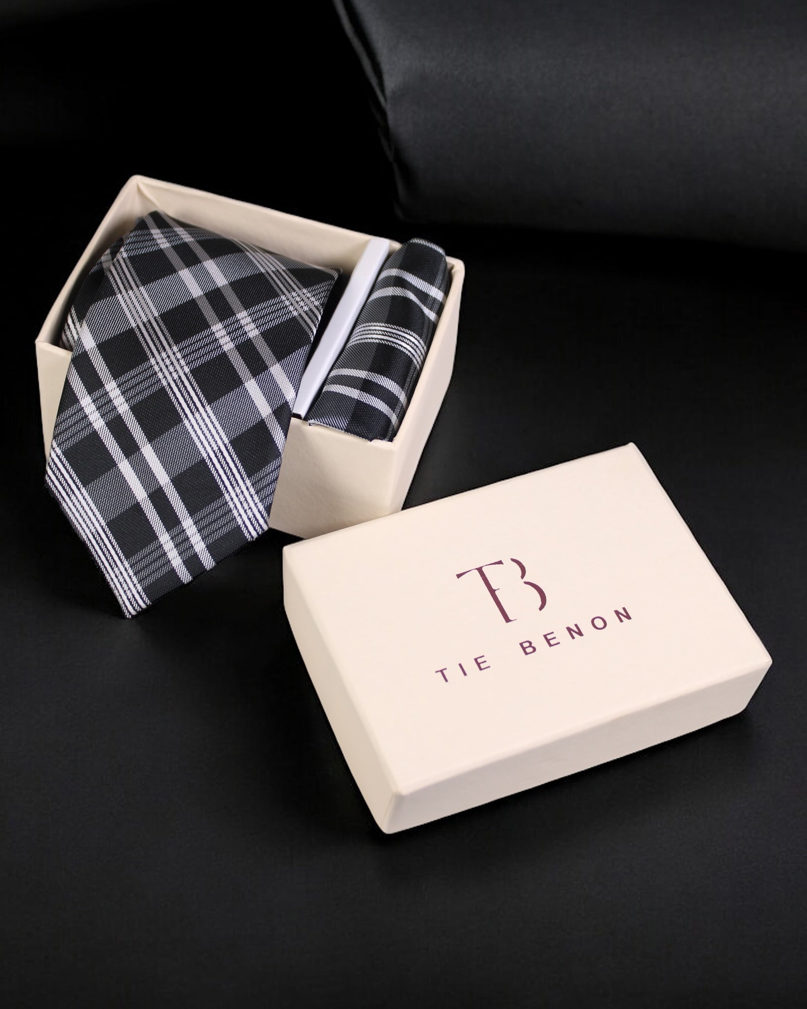 Plaid tie in an open box with 'Tie Benon' branding on a black background