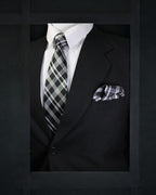 Black suit with plaid tie and pocket square on a dark background