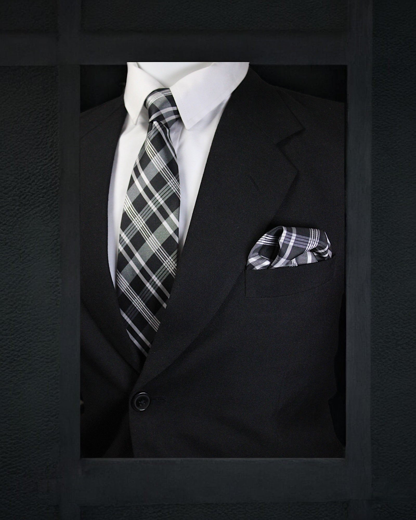 Black suit with plaid tie and pocket square on a dark background
