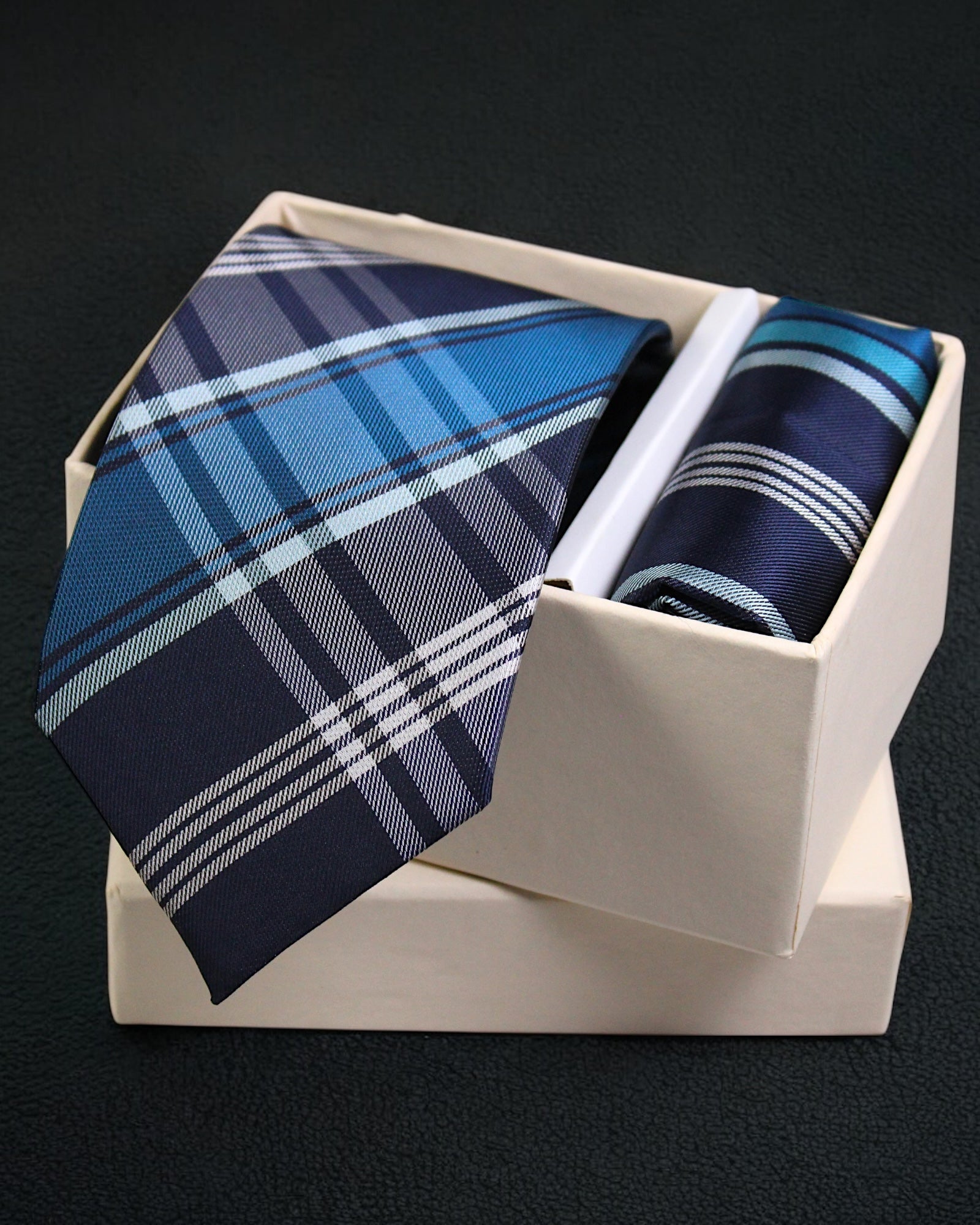 Two plaid ties in a white box on a black background