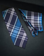 Blue plaid tie and pocket square on a dark surface