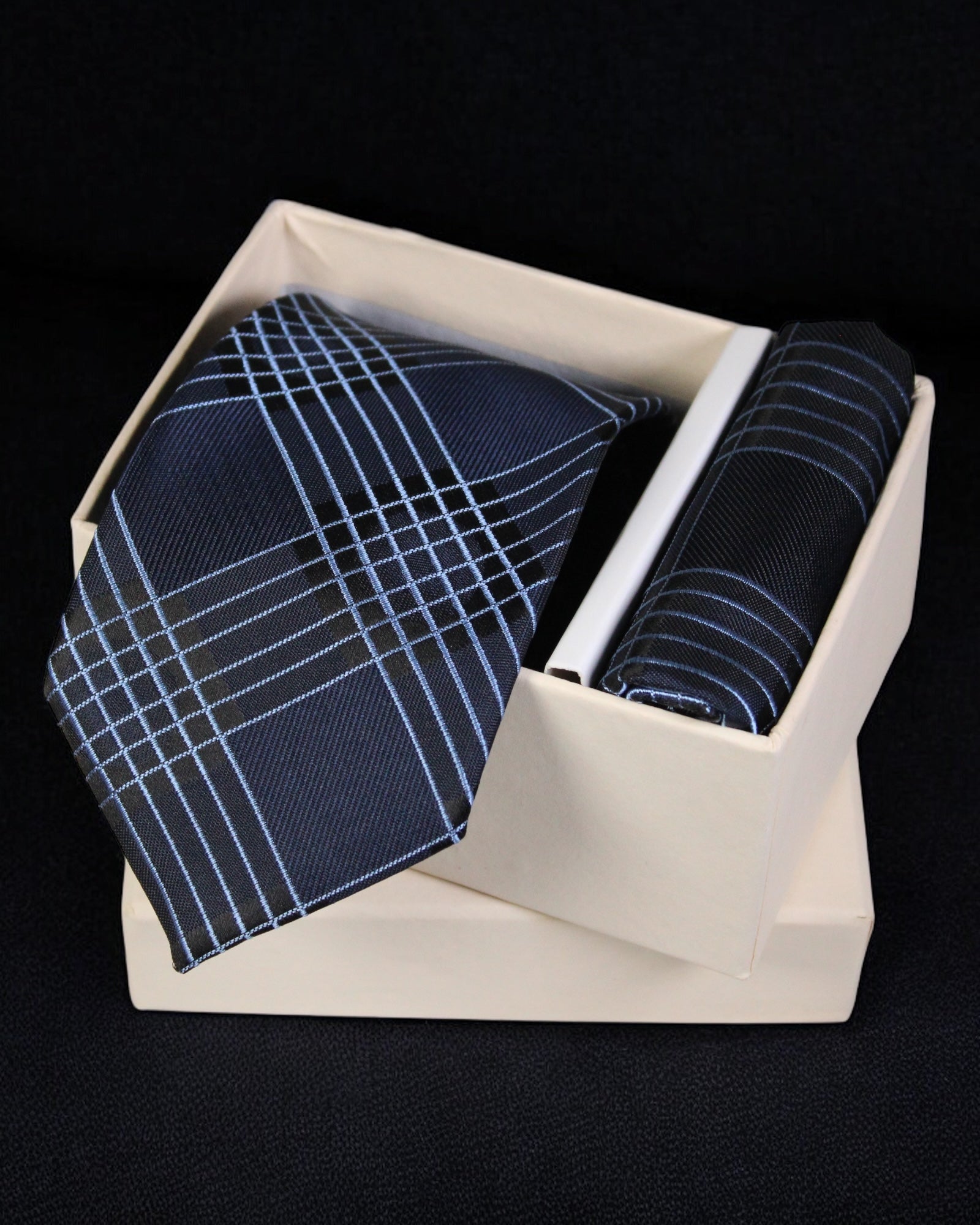 Set of blue patterned tie and pocket square in a white box on a black background tie benon 