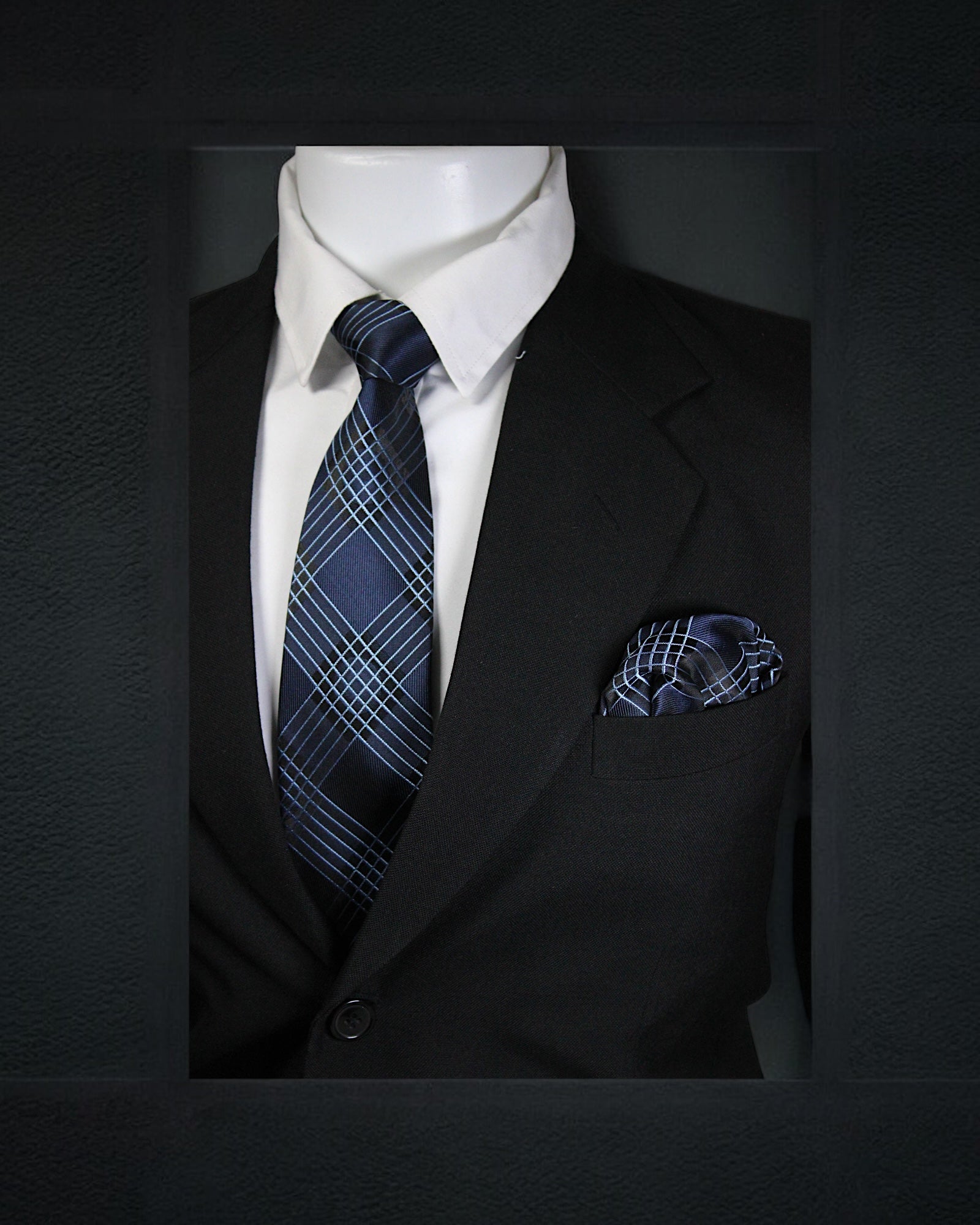 Mannequin wearing a black suit with a blue plaid tie and pocket square on a dark background Tie Benon