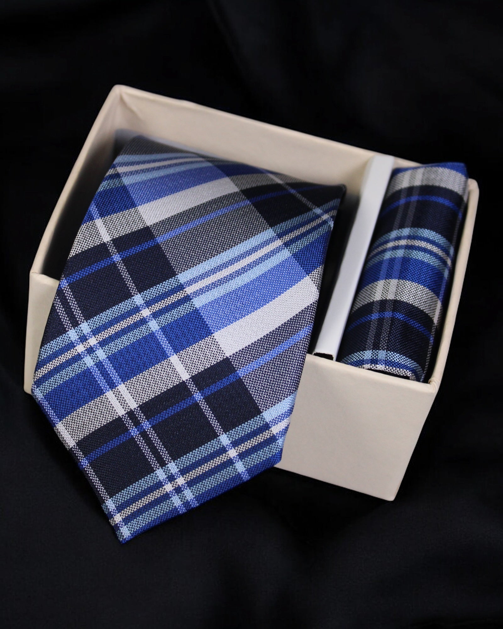 Blue plaid tie and pocket square set in a white box on a black background