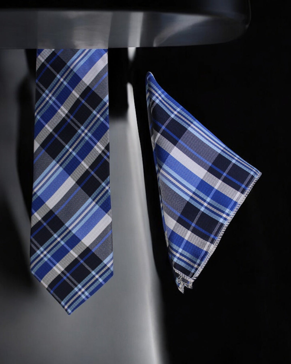 Blue plaid tie and pocket square set on a black background