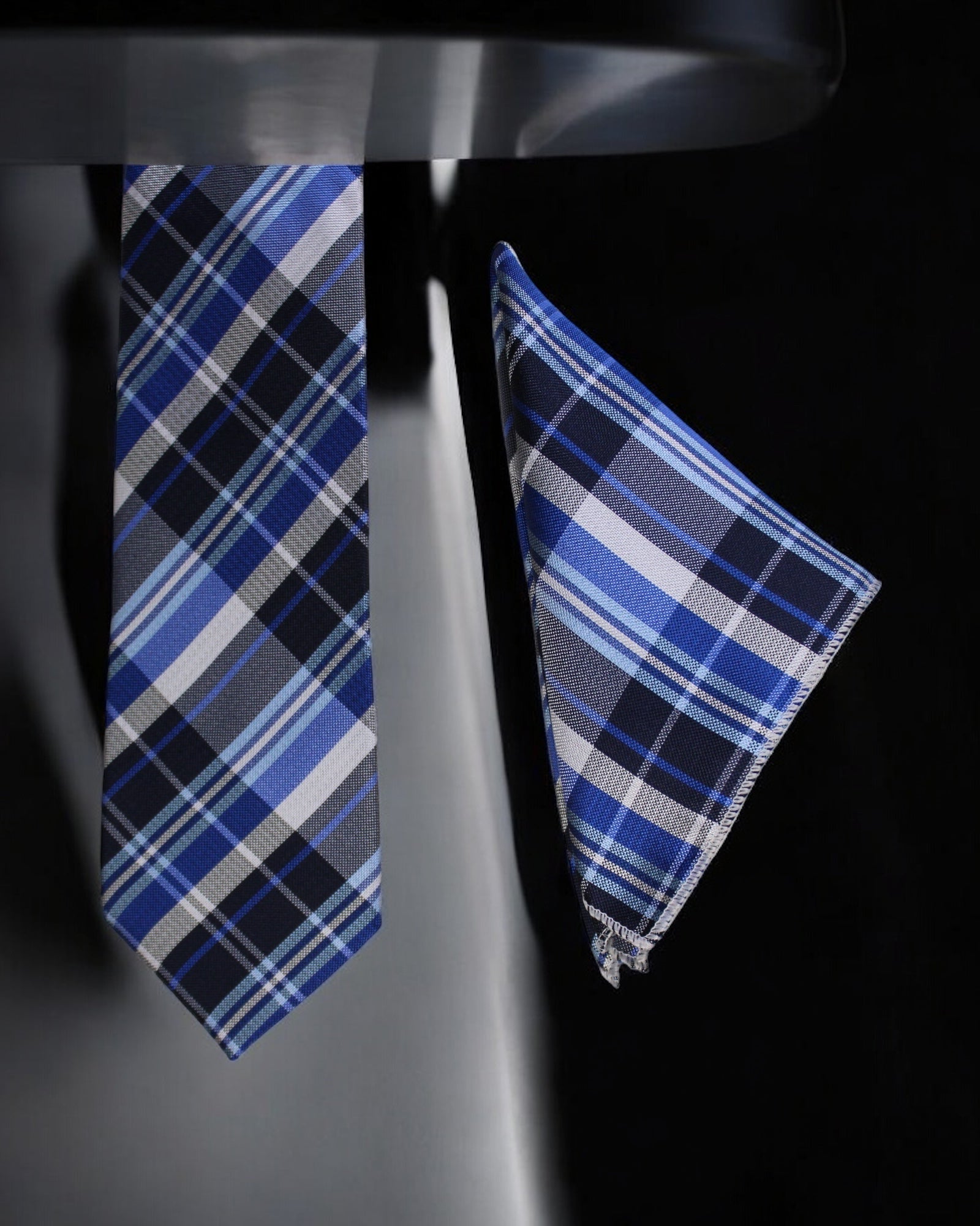Blue plaid tie and pocket square set on a black background