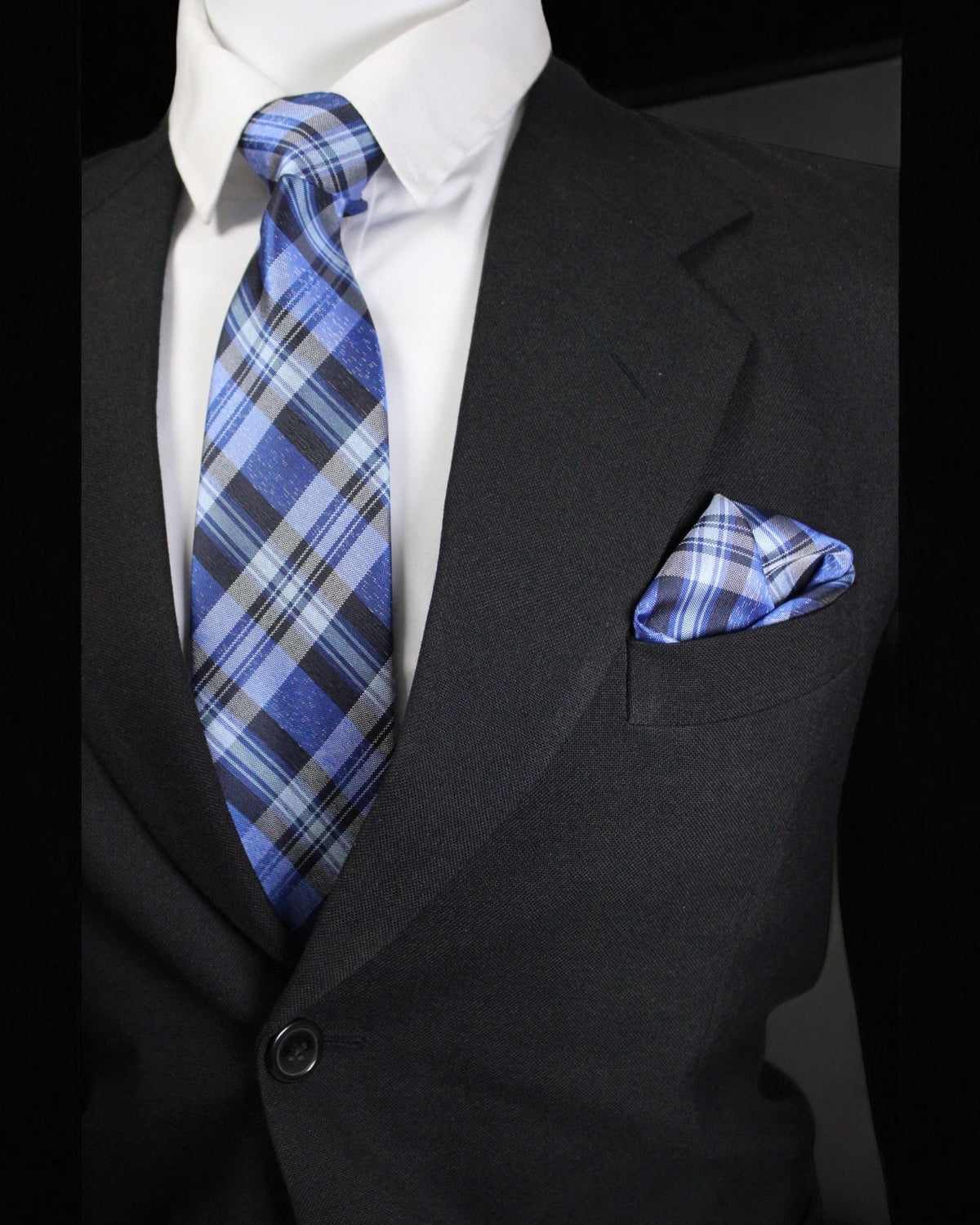 Black suit with blue plaid tie and pocket square on a black background Tie Benon
