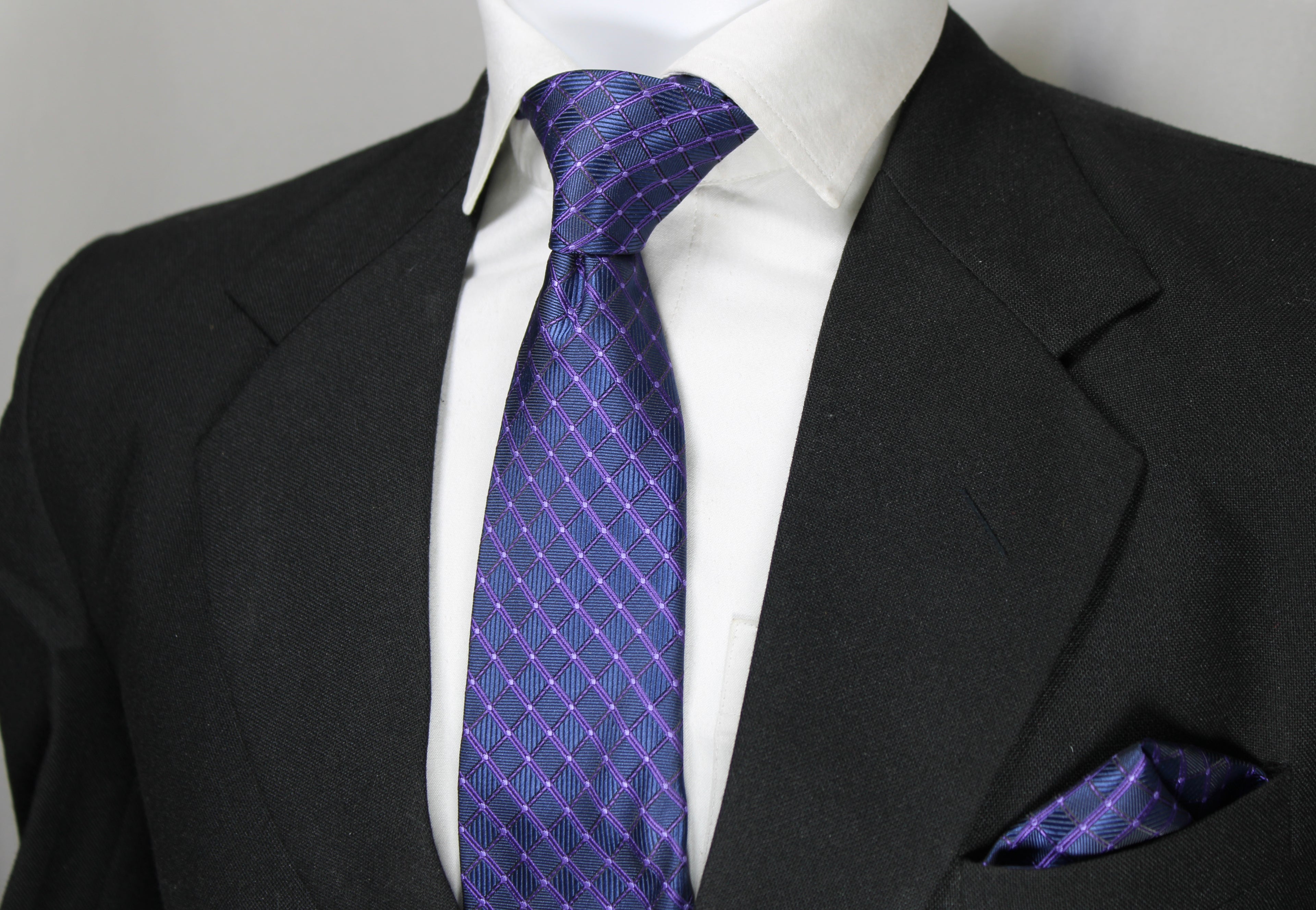 A photo showing a Blue & Purple Checkered Tie & Pocket Square set, with the tie worn in a standard knot and the pocket square placed in the breast pocket of a suit jacket.
