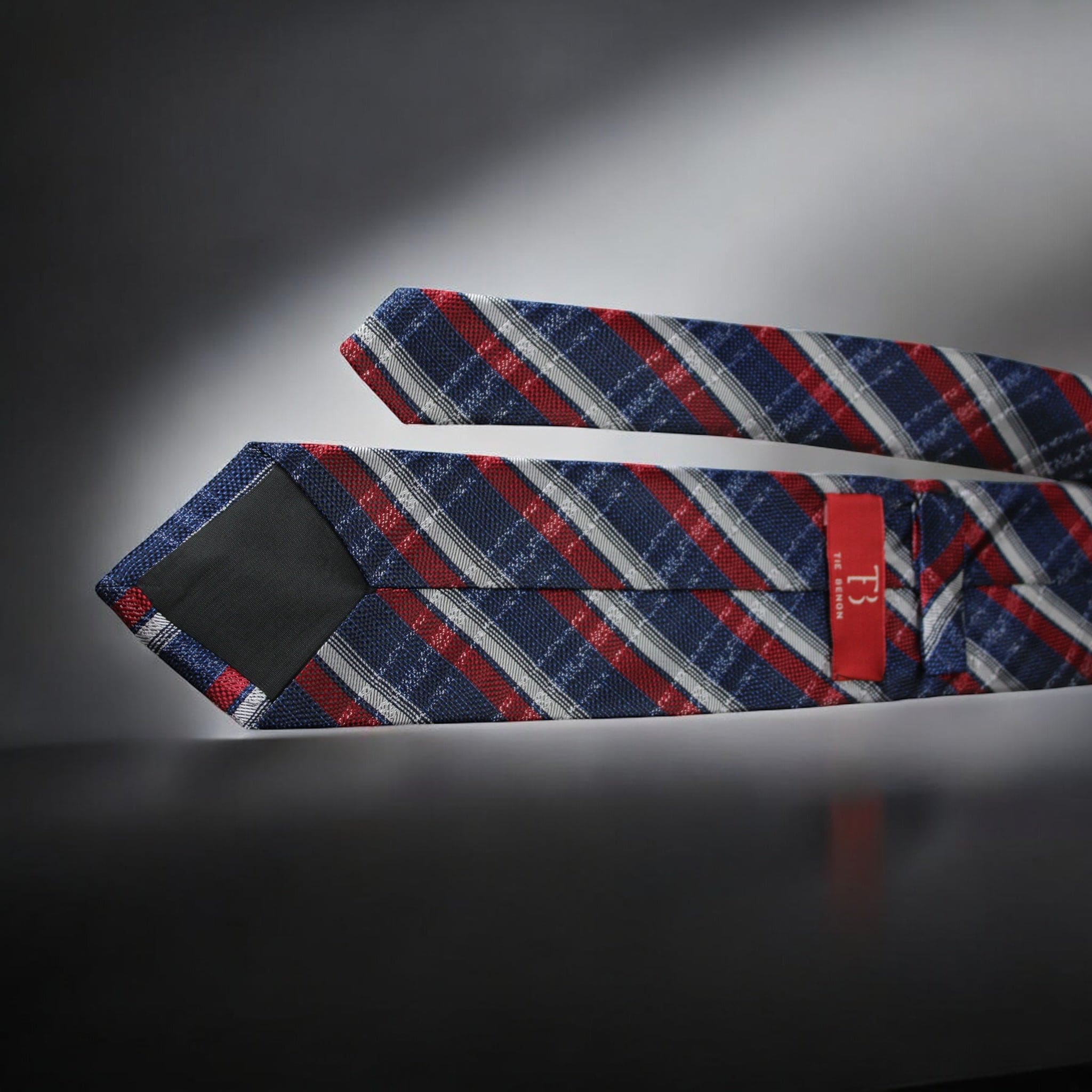 Blue, red, and white striped tie with a red label on a dark background