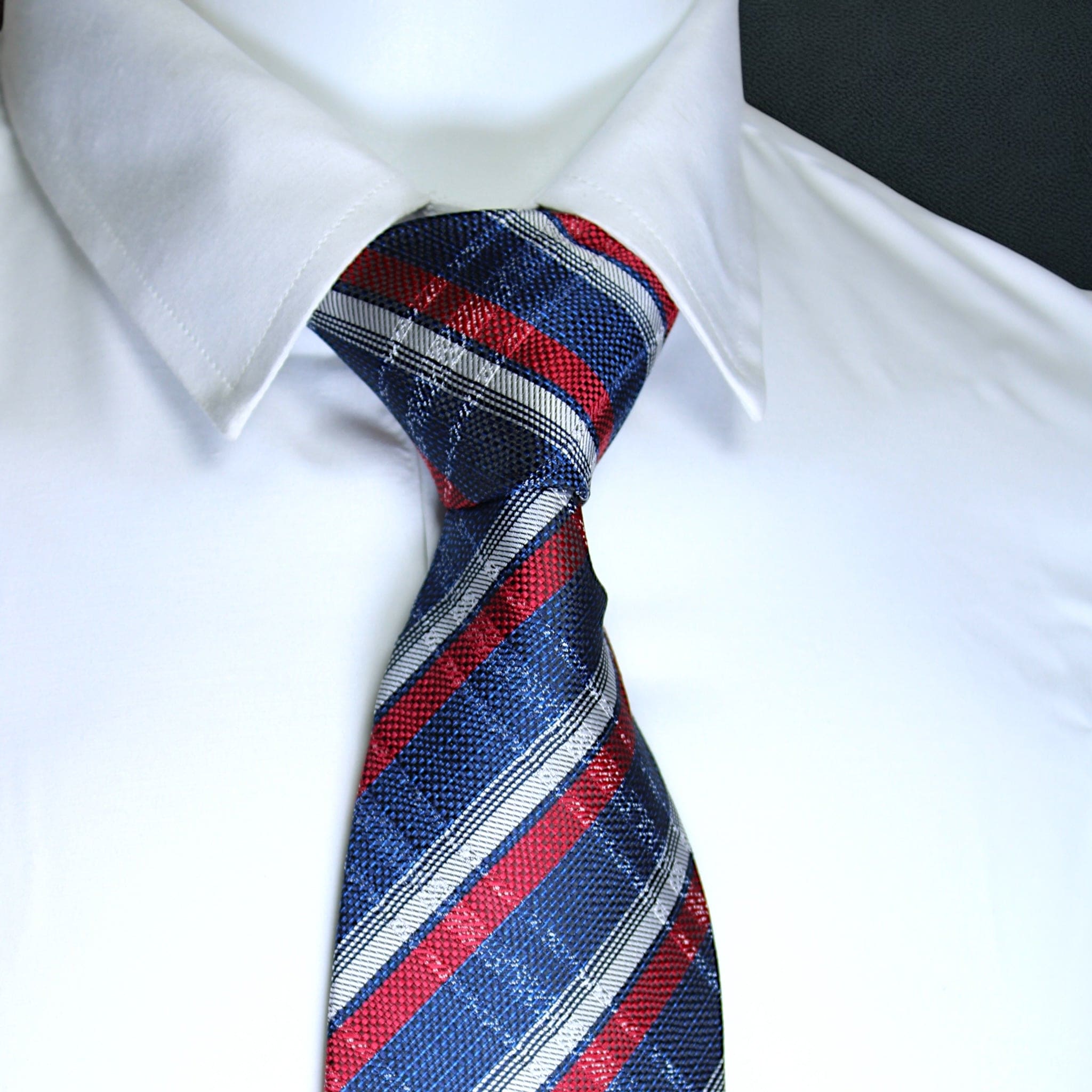 Red, blue, and gray striped tie on a white shirt with a black background