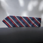 Striped tie with red, blue, and gray pattern on a dark surface