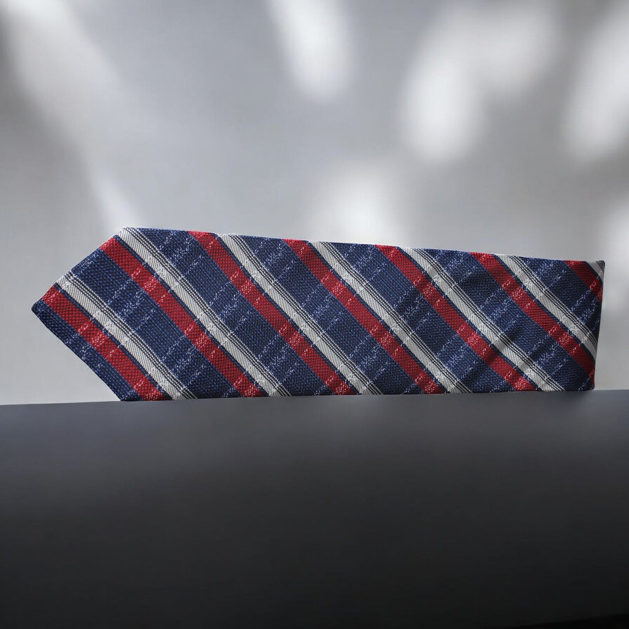Striped tie with red, blue, and gray pattern on a dark surface