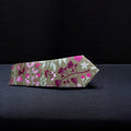 A brown and pink floral tie with a matching pocket square laid out flat on a dark background.
