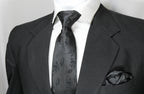 A black floral tie and pocket square set displayed on a mannequin wearing a black suit and white shirt.
