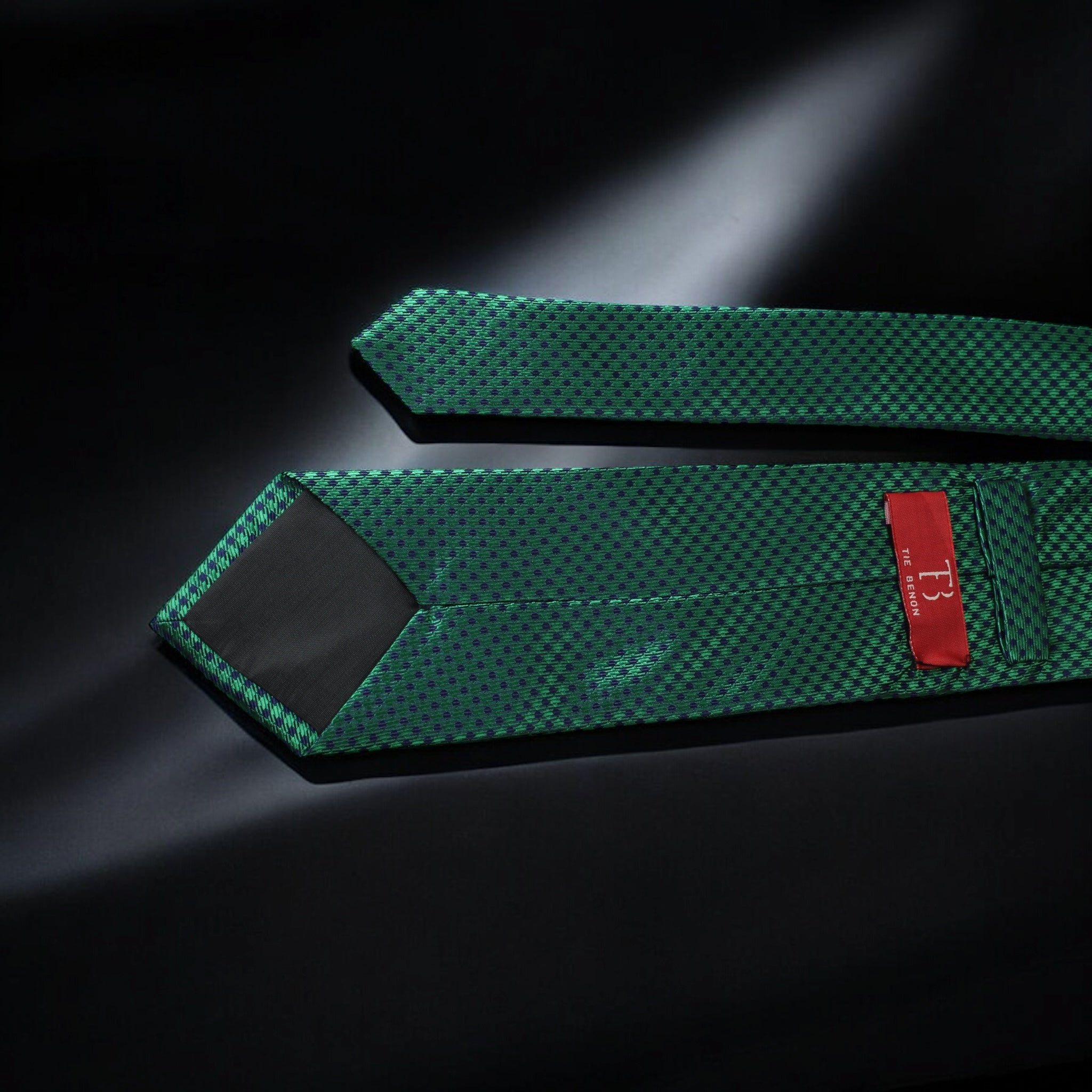 Two green textured straps with a red label on a dark background