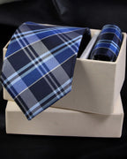 Blue plaid tie and pocket square set on a white box with a black background