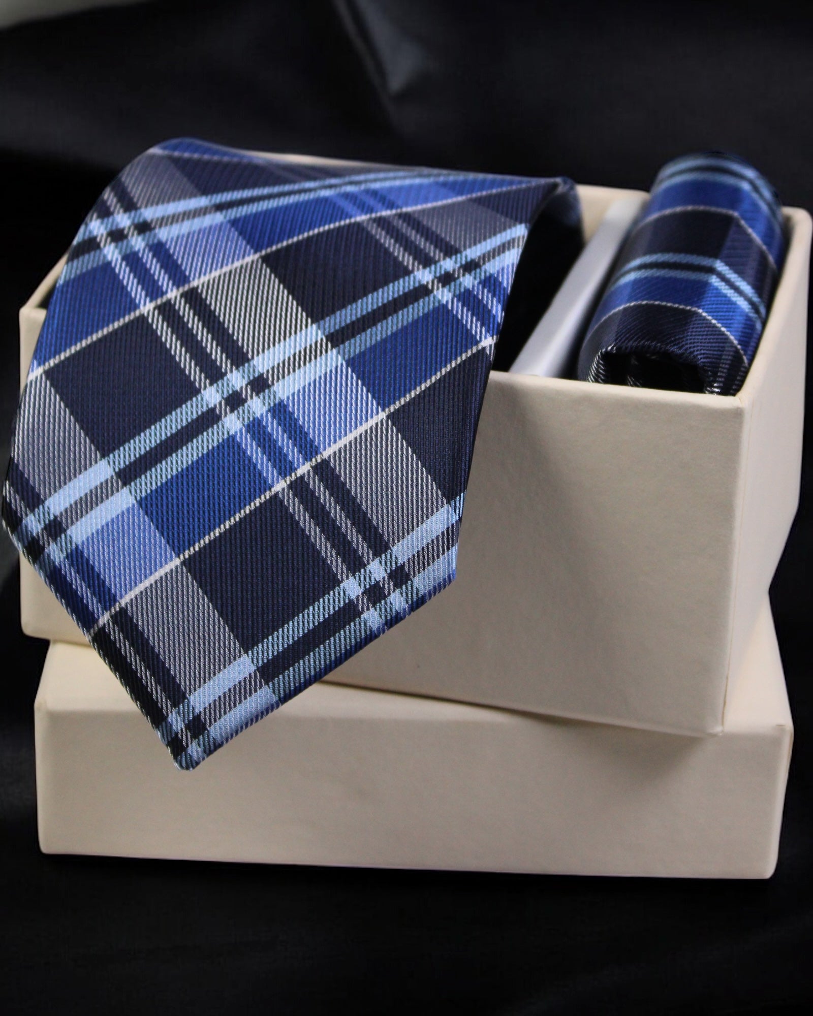 Blue plaid tie and pocket square set on a white box with a black background
