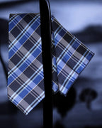 Blue and gray plaid tie and pocket square on a dark background