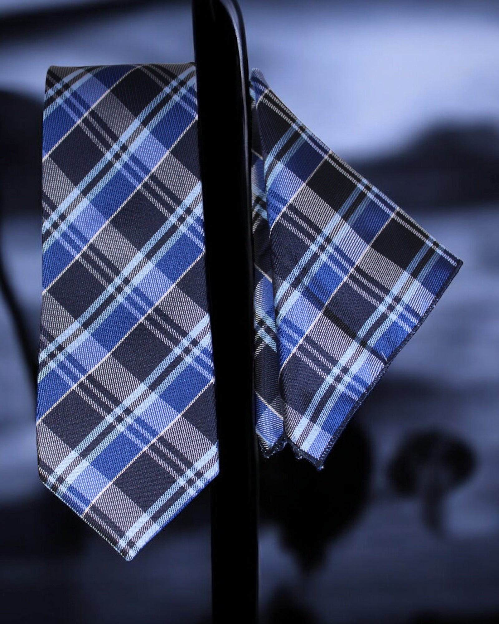 Blue and gray plaid tie and pocket square on a dark background