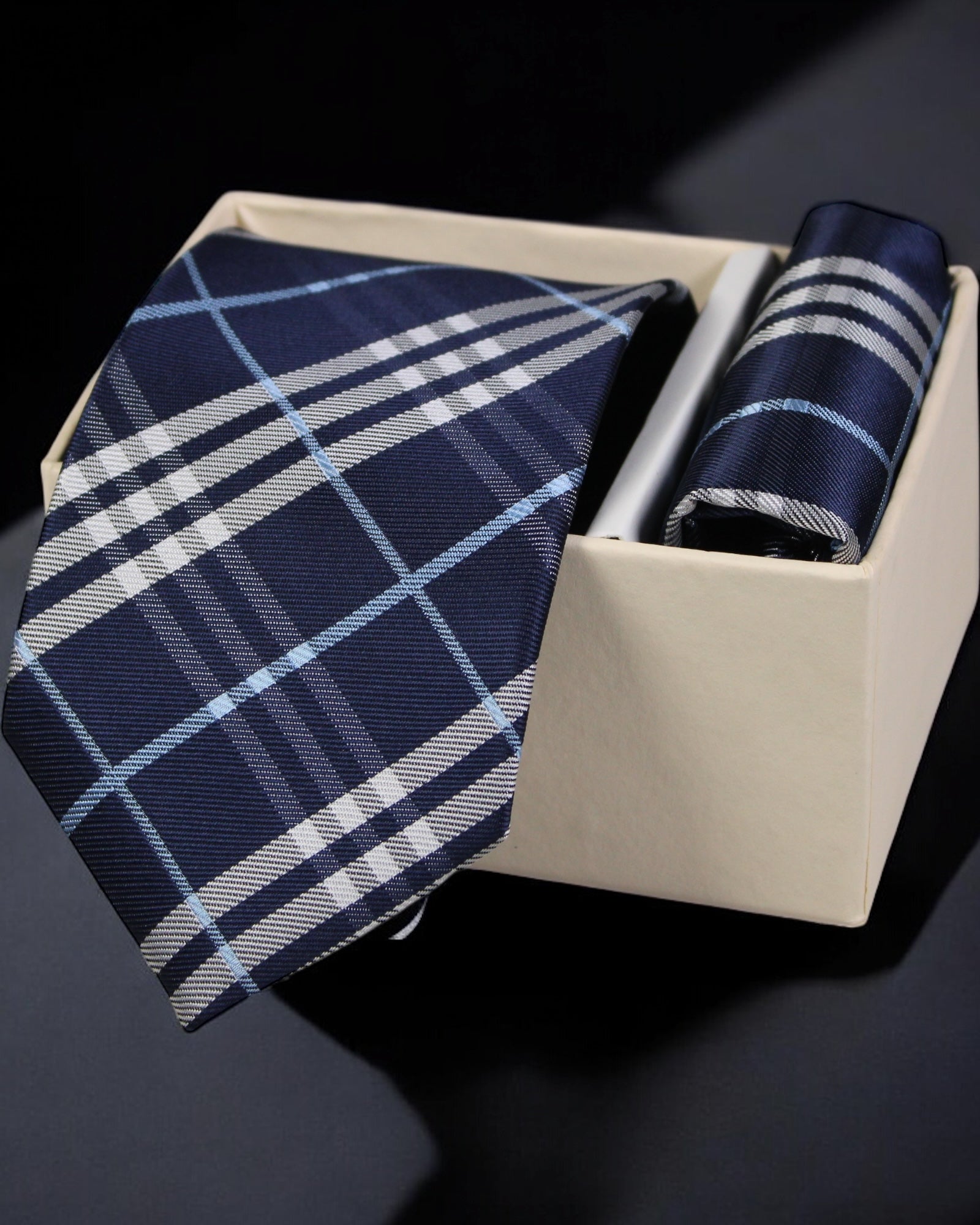 Navy and white plaid tie and pocket square set in a beige box on a dark background Tie Benon