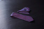 A navy and maroon polka tie laid out flat on a dark surface.