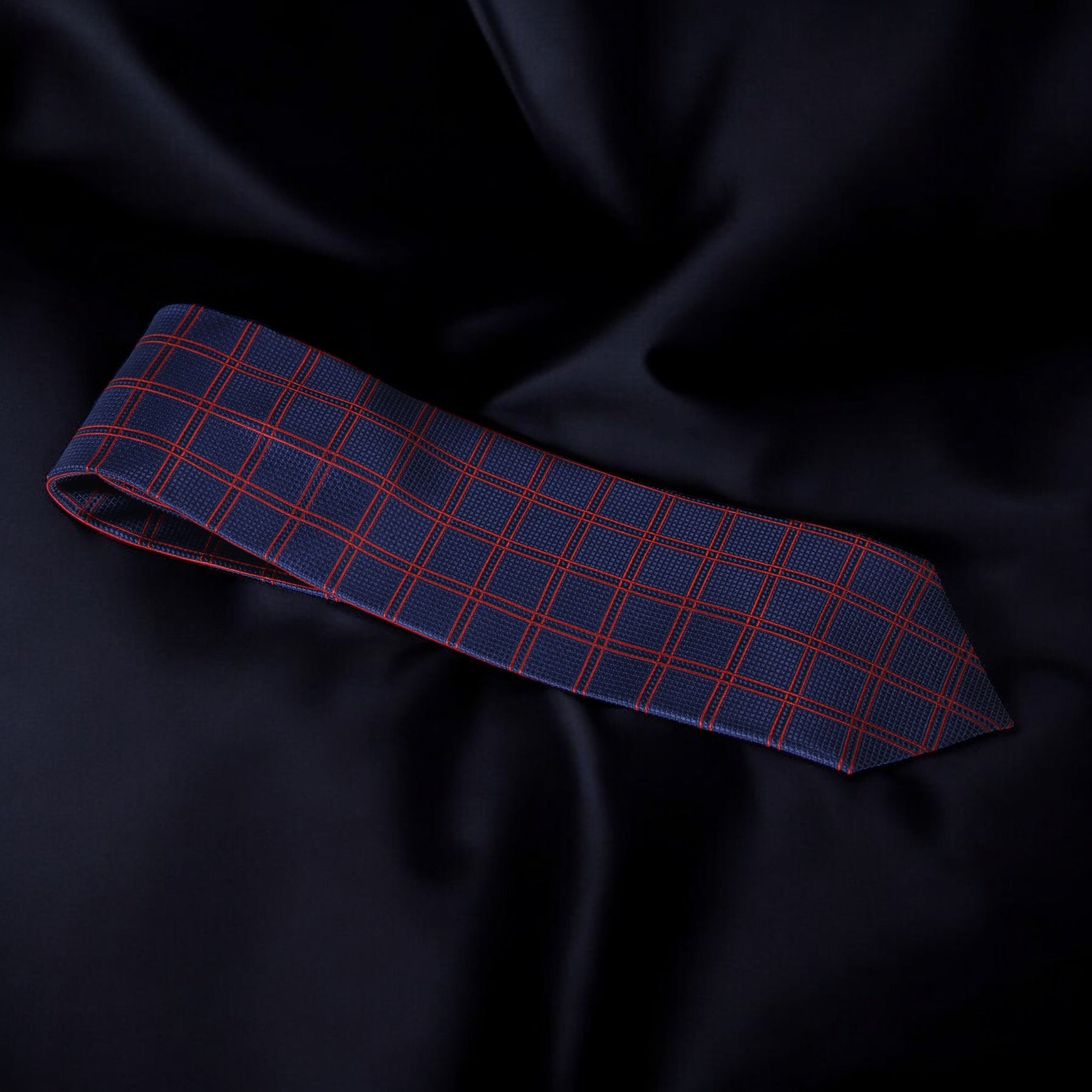 Blue and red checkered tie on a dark fabric background