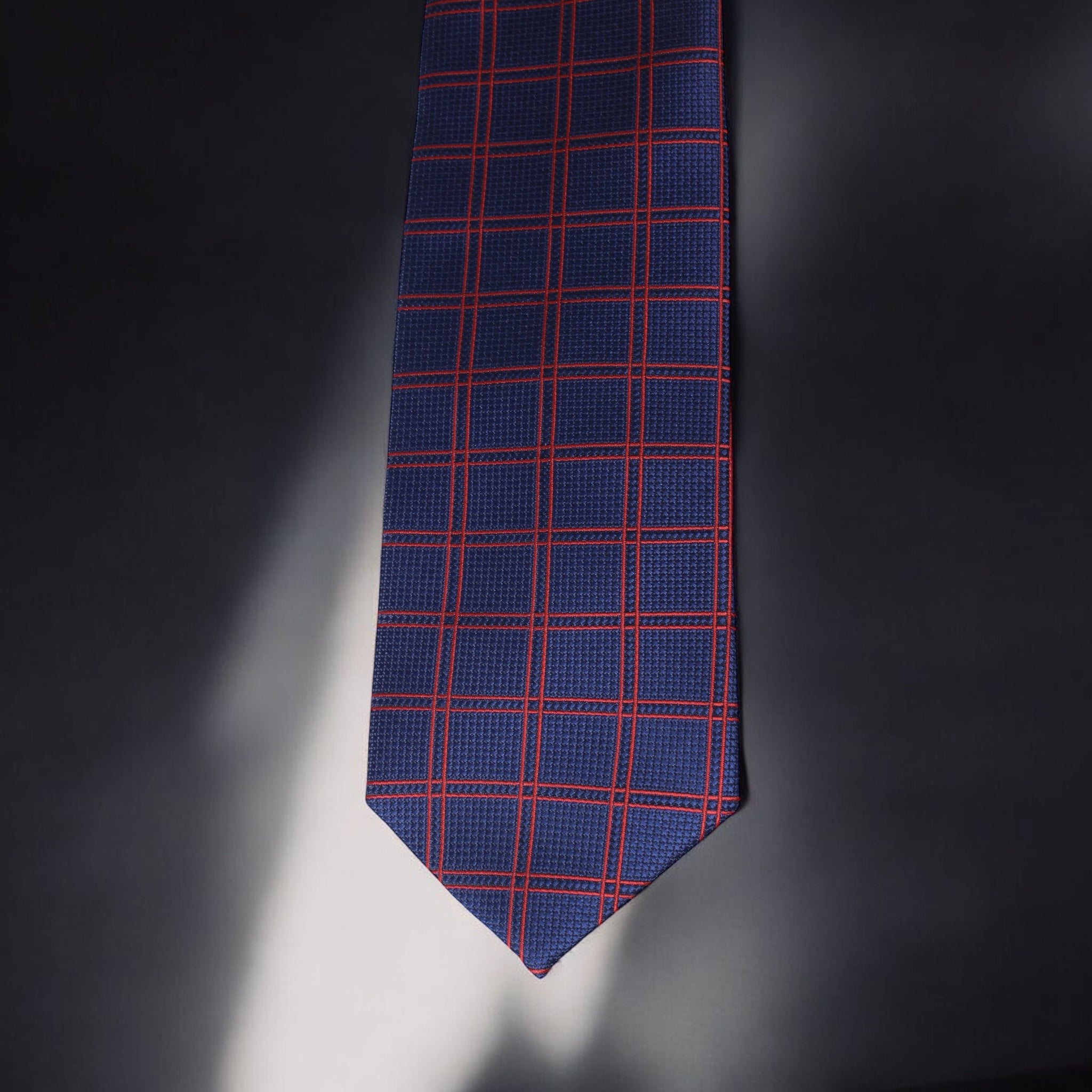 Blue tie with red plaid pattern on a dark background