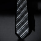 Black and gray striped tie on a dark background