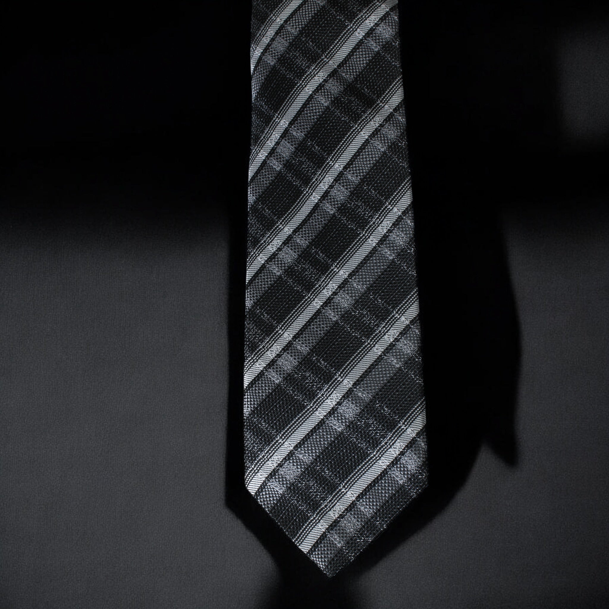 Black and gray striped tie on a dark background