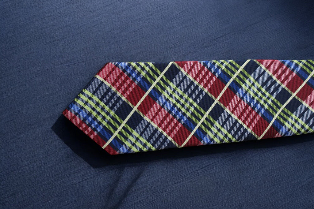 Plaid tie with red, blue, and yellow pattern on a dark fabric background