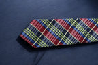 Plaid tie with red, blue, and yellow pattern on a dark fabric background