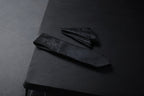 A black floral tie and pocket square set on a dark background.