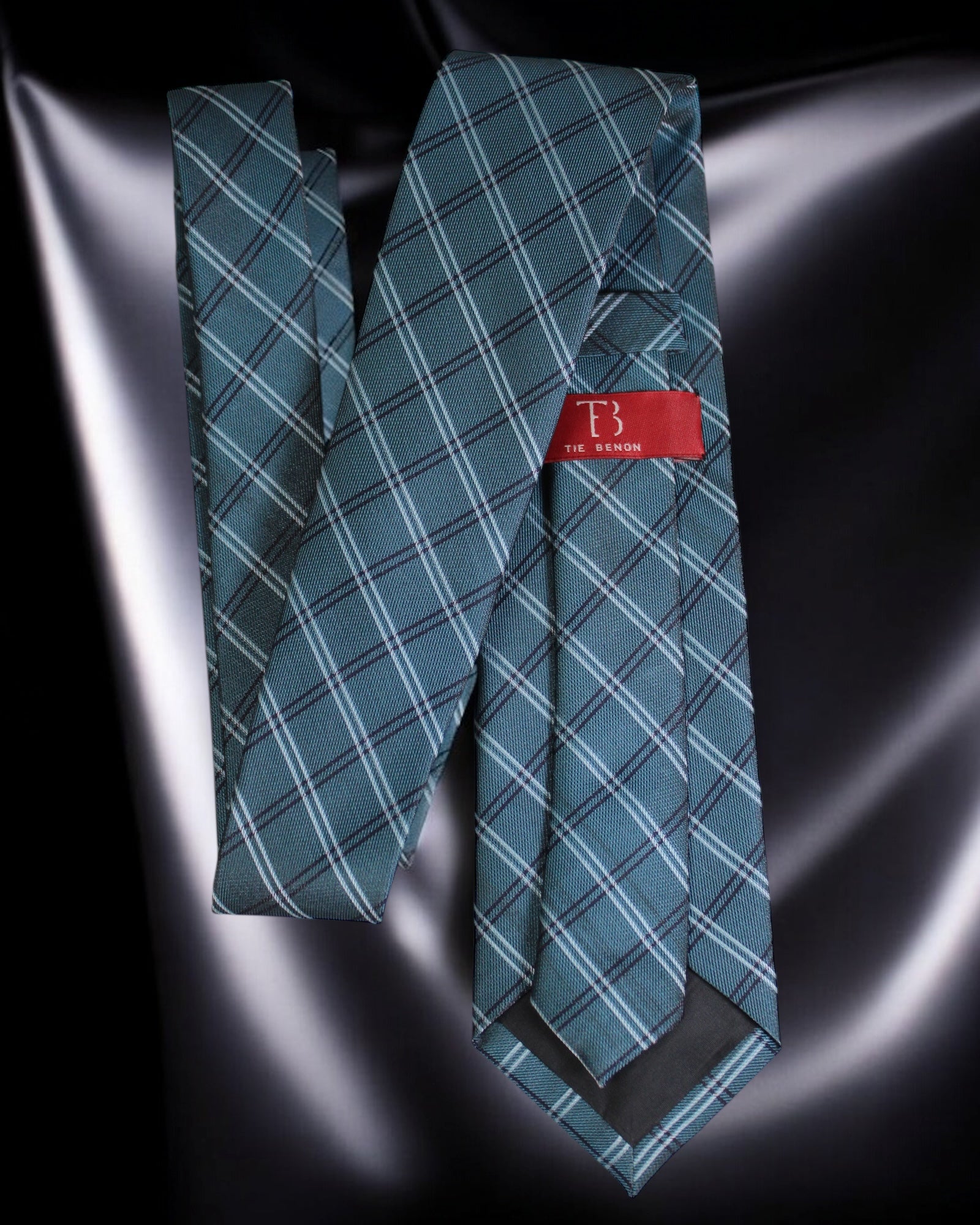 Teal plaid tie with a red label on a reflective black surface Tie Benon