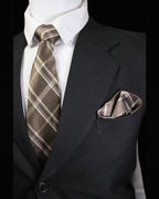 Man wearing a black suit with a brown plaid tie and pocket square against a black background Tie Benon