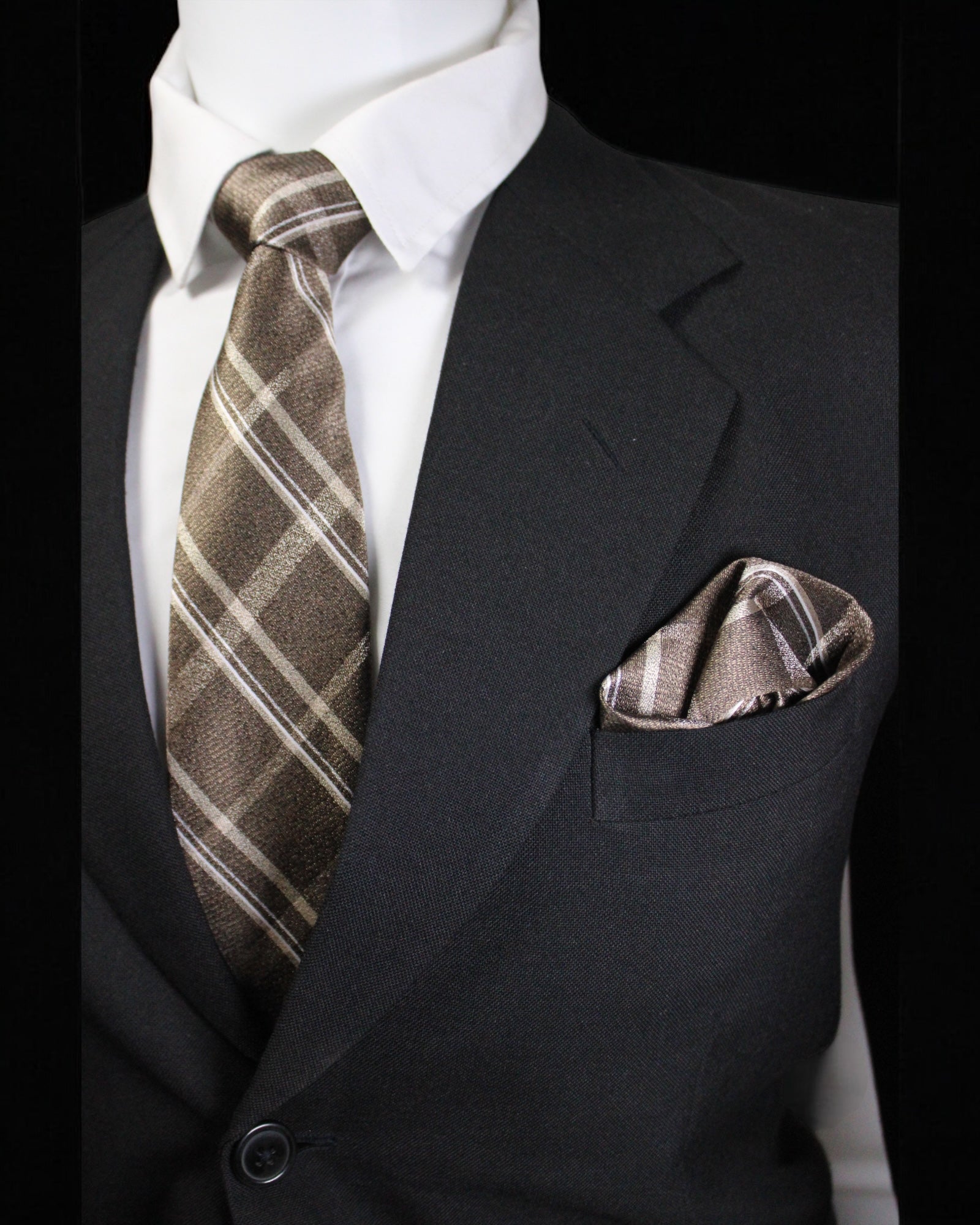 Man wearing a black suit with a brown plaid tie and pocket square against a black background Tie Benon