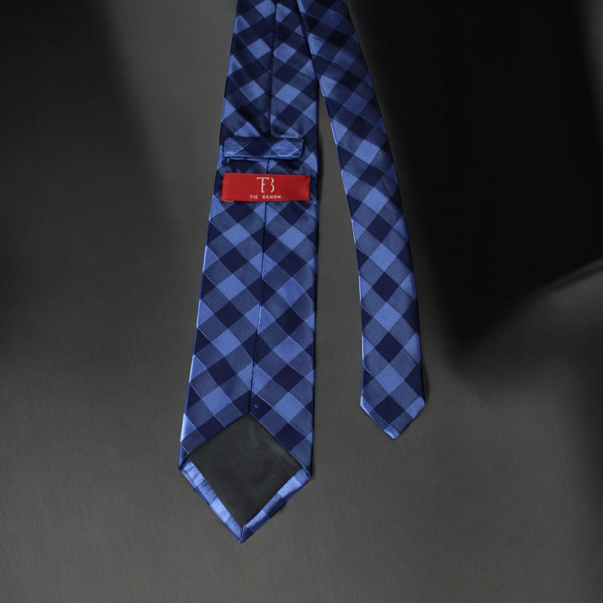 Blue checkered tie with a red label on a dark background
