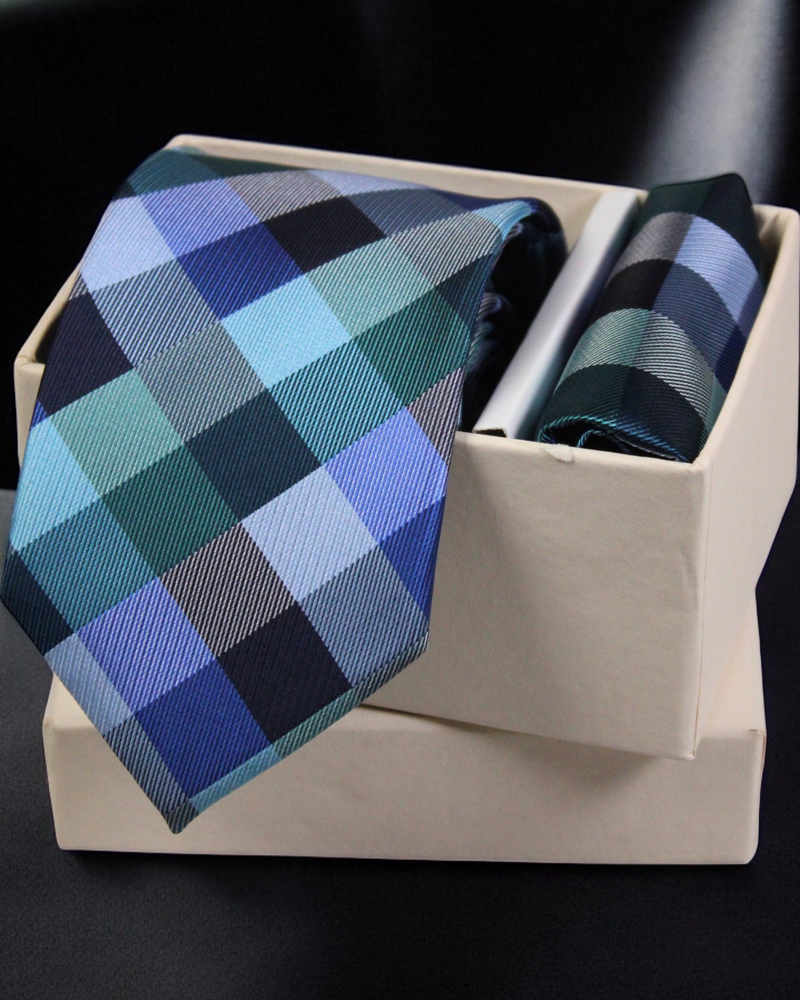 Blue and green checkered tie with matching pocket square in a box on a black background Tie Benon