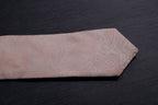Pink paisley tie on a dark surface