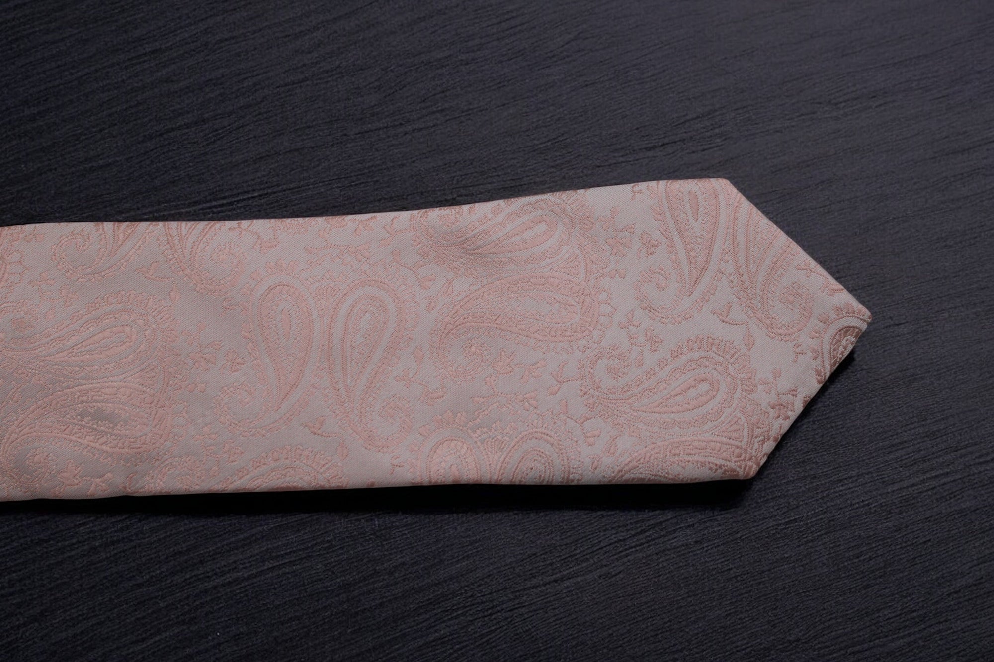 Pink paisley tie on a dark surface