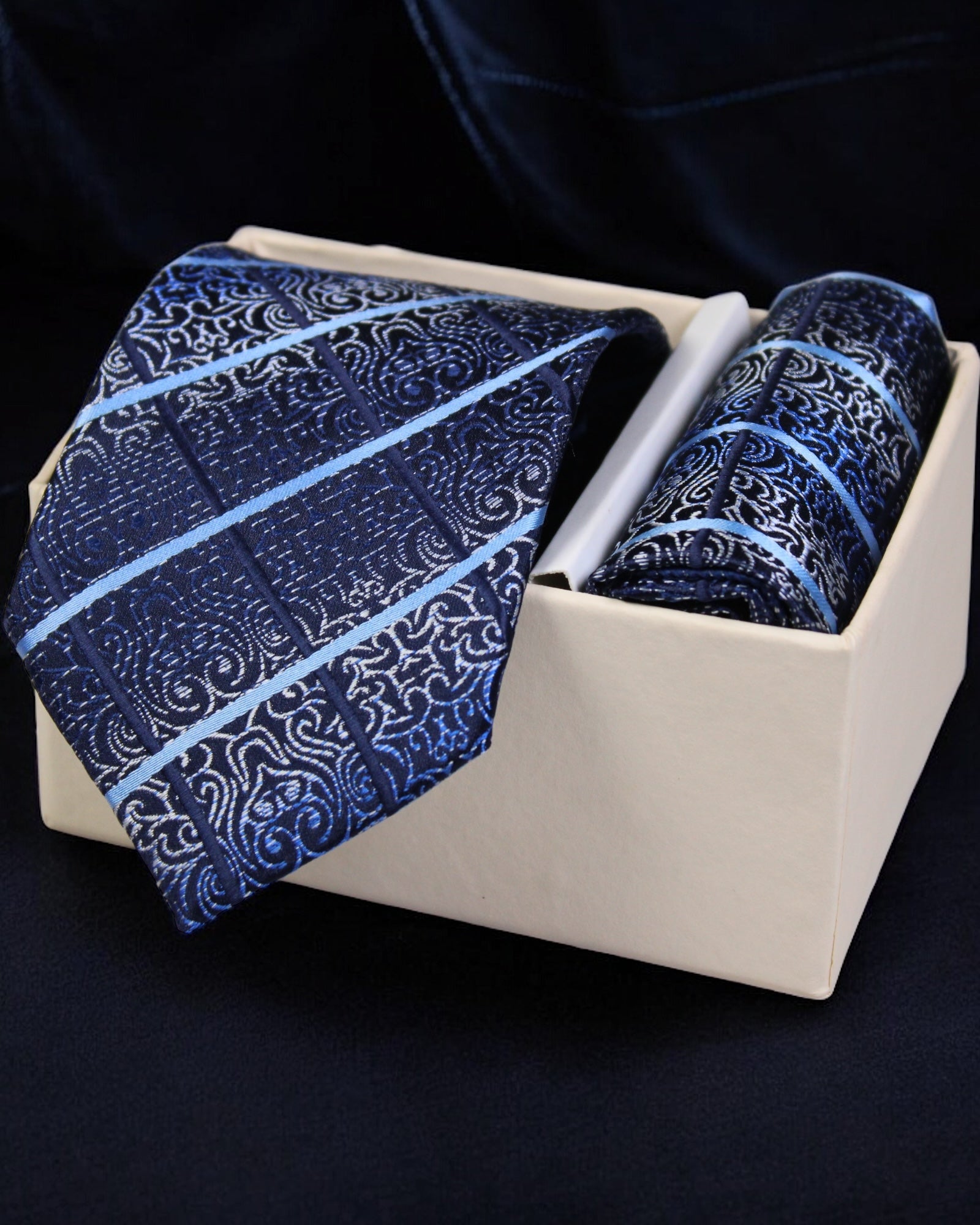 Blue patterned tie and pocket square set in a white box on a dark background Tie Benon