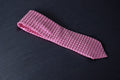 A pink checkered microsilk necktie on a dark background.