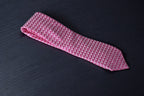 A pink checkered microsilk necktie on a dark background.