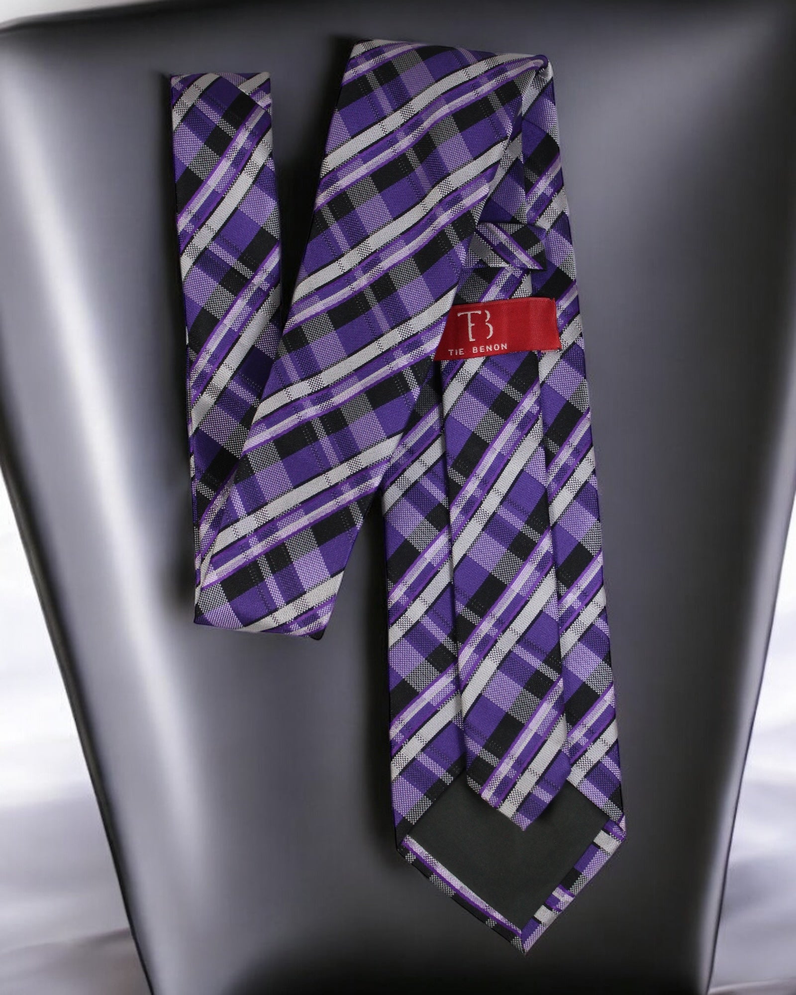 Purple plaid tie with a red label on a gray surface tie benon
